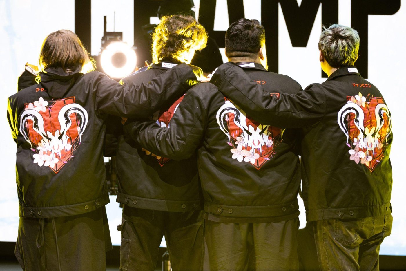Players on stage wearing custom embroidered championship jackets
